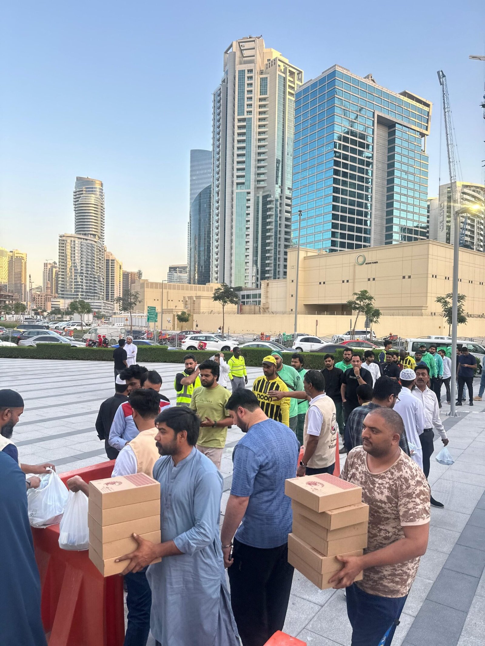 A group of people in Dubai waiting to collect meal boxes, highlighting community efforts in affordable office lunch catering.